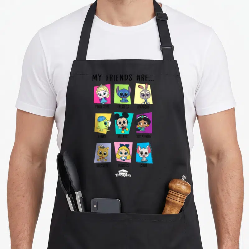 Tablier de cuisine noir avec illustration My Friends Are montrant neuf personnages Disney Pixar Doorables sur fonds colorés.