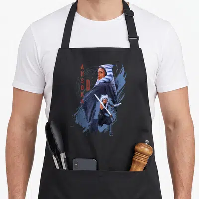 Tablier de cuisine noir avec illustration d'Ahsoka Tano Jedi Ready tenant une épée lumineuse sur fond bleu stylisé.