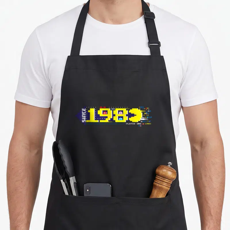 Tablier de cuisine noir avec motif Pac-Man pixel art jaune et texte Since 1980 Player One