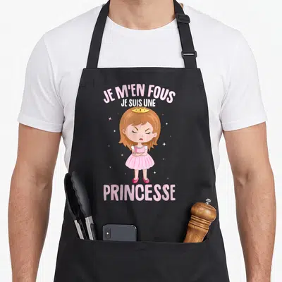Tablier de cuisine noir avec une illustration de princesse boudeuse et le texte Je m'en fous je suis une princesse en rose et blanc.