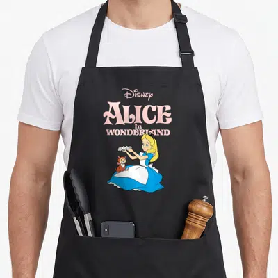 Tablier de cuisine noir avec Alice au pays des merveilles offrant des fleurs à Dinah en illustration colorée.