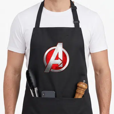 Tablier de cuisine noir avec le logo circulaire des Avengers en rouge vif et métal argenté brillant au centre.