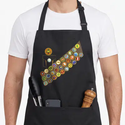 Tablier de cuisine noir orné de multiples badges colorés représentant les activités de l'explorateur Russell et son logo We Explore.