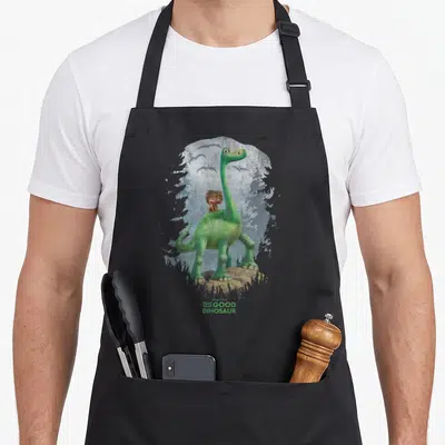 Tablier de cuisine noir avec illustration d'un dinosaure vert portant un petit garçon sur son dos face à des arbres.