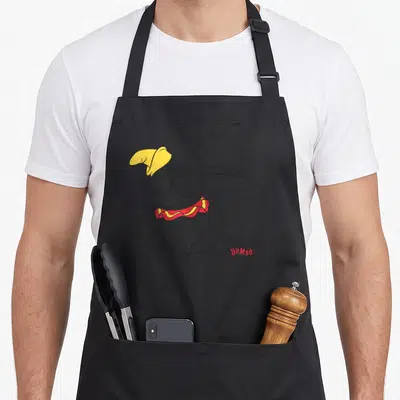 Tablier de cuisine noir avec un Dumbo assis au chapeau jaune et collier rouge.