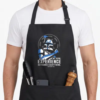 Tablier de cuisine noir avec illustration du Captain Rex et la phrase In my book experience outranks everything en blanc et bleu.