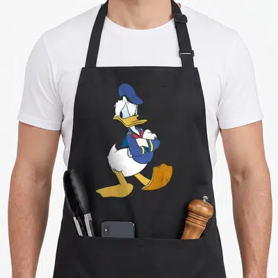 Tablier de cuisine noir avec illustration de Donald Duck en posture furieuse, bras croisés et regard mécontent.