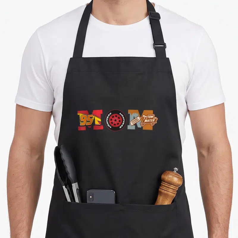 Tablier de cuisine noir avec le mot Mom stylisé en lettres de voitures de course et remorque orange.