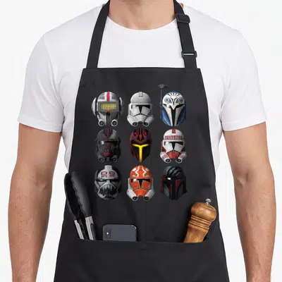 Tablier de cuisine noir avec neuf casques de clone et de guerriers colorés disposés en grille.