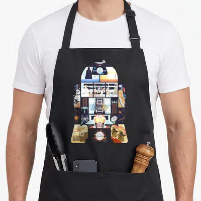 Tablier de cuisine noir avec une grande illustration colorée en forme de robot R2-D2 contenant des scènes de personnages et de planètes.