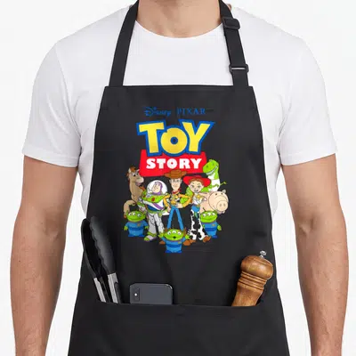 Tablier de cuisine noir avec le logo Toy Story et les personnages Buzz, Woody, Jessie, Rex ainsi que trois petits aliens verts en bas.