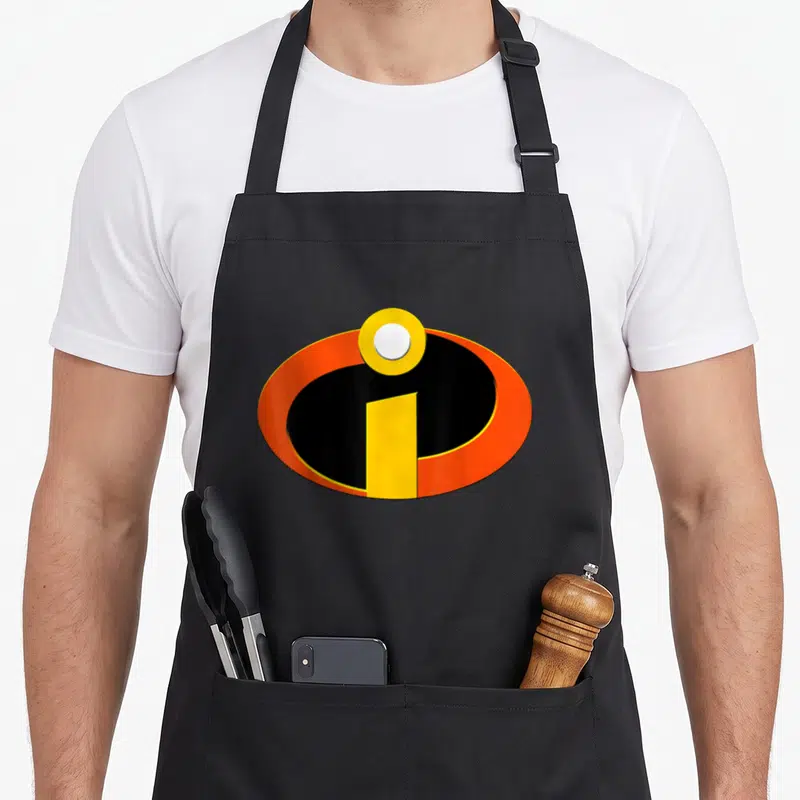 Tablier de cuisine noir avec le logo des Indestructibles en orange noir et jaune au centre.