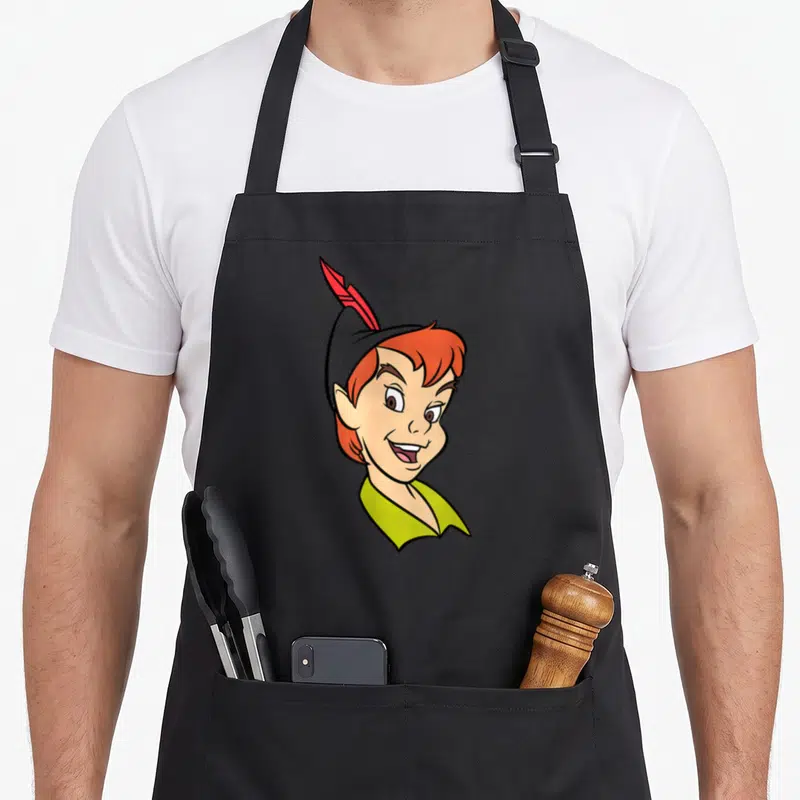 Tablier de cuisine noir avec le visage souriant de Peter Pan portant une coiffe à plume rouge et un col vert