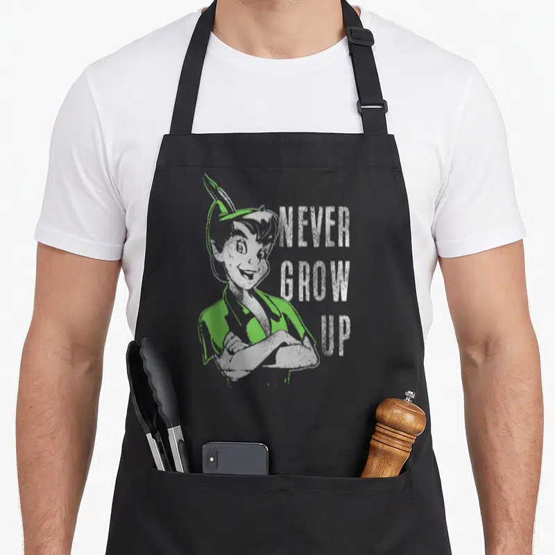 Tablier de cuisine noir avec portrait vintage de Peter Pan et texte NEVER GROW UP en blanc et vert.