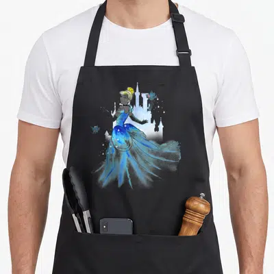 Tablier de cuisine noir avec illustration aquarelle de Cendrillon en robe bleue scintillante et silhouettes de château en arrière-plan.