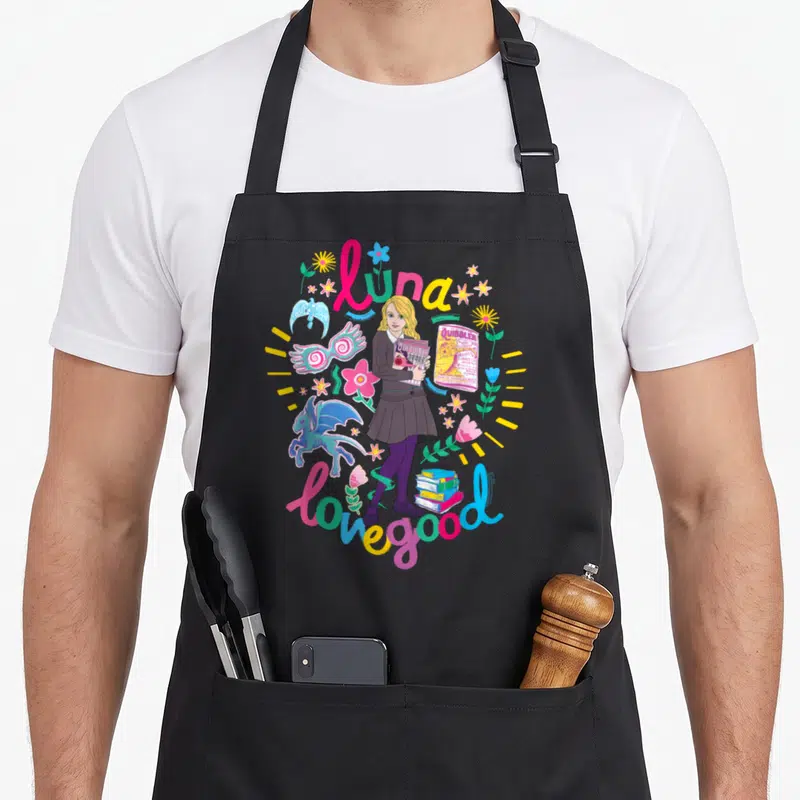 Tablier de cuisine noir avec illustration colorée de Luna Lovegood tenant le Quibbler et des créatures fantastiques.