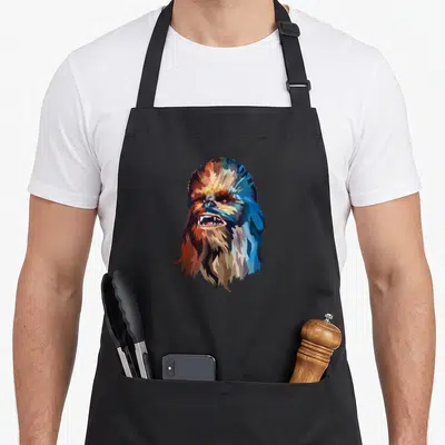 Tablier de cuisine noir avec portrait stylisé de Chewbacca aux teintes géométriques multicolores et expression intense.
