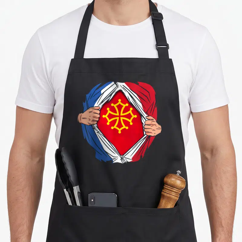 Tablier de cuisine noir avec illustration super-héros déchirant un vêtement tricolore pour montrer une croix occitane rouge et jaune.