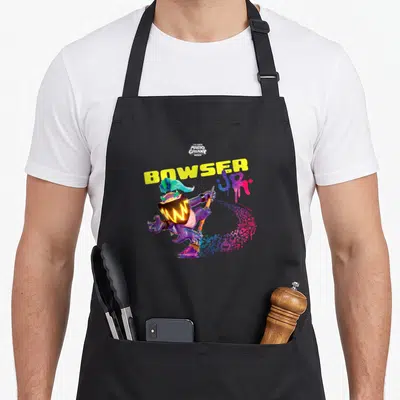 Tablier de cuisine noir avec illustration de Bowser Jr. en action, casque jaune et texte graffiti violet et bleu.
