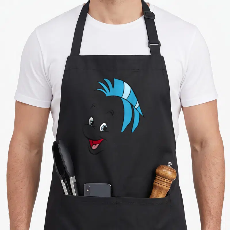 Tablier de cuisine noir avec le visage souriant et expressif du poisson Flounder aux rayures bleues