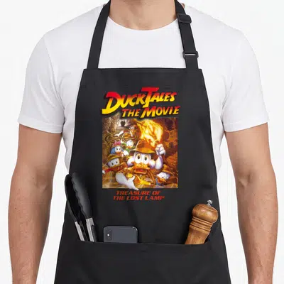 Tablier de cuisine noir avec illustration couleur de DuckTales The Movie et le titre Treasure of the Lost Lamp en bas.