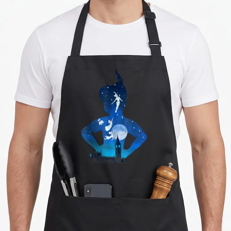 Tablier de cuisine noir avec silhouette bleue de Peter Pan contenant une lune, Tinker Bell et Big Ben sur fond étoilé.