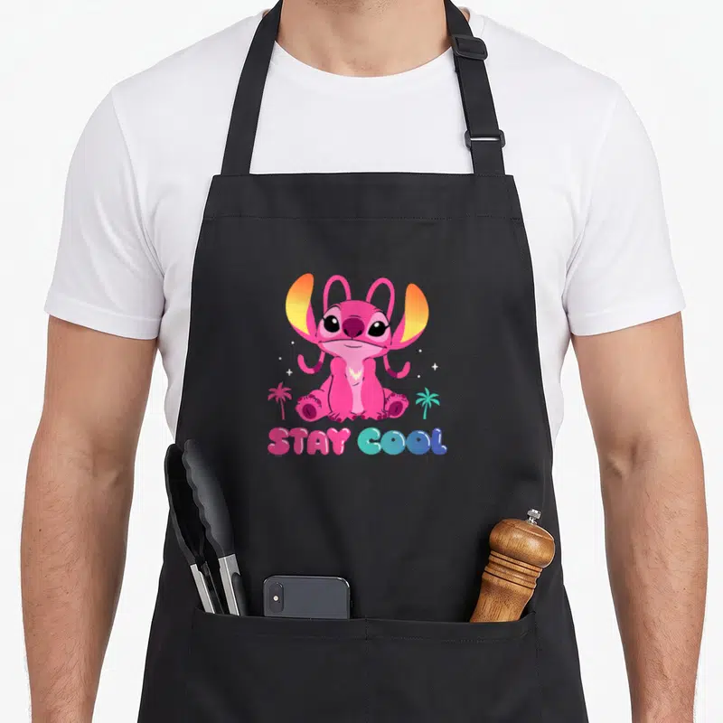 Tablier de cuisine noir avec un ange rose Disney et le texte Stay Cool en lettres bulles multicolores.