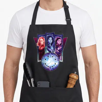 Tablier de cuisine noir avec Captain Marvel, Photon et Ms. Marvel encadrés par une étoile cosmique lumineuse.