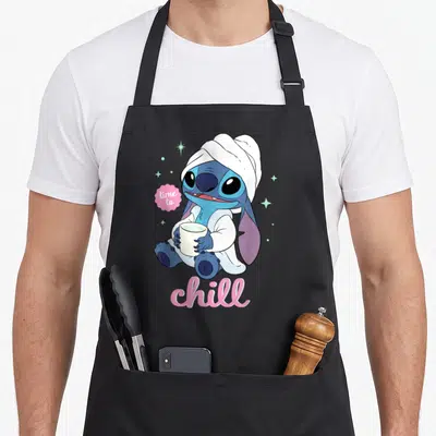 Tablier de cuisine noir avec Stitch enveloppé dans une serviette tenant une tasse blanche.