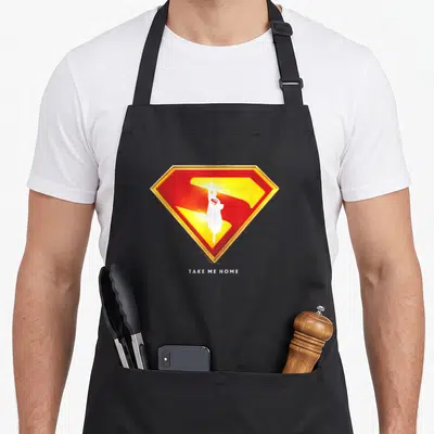 Tablier de cuisine noir avec un logo Superman Take Me Home rouge jaune et blanc
