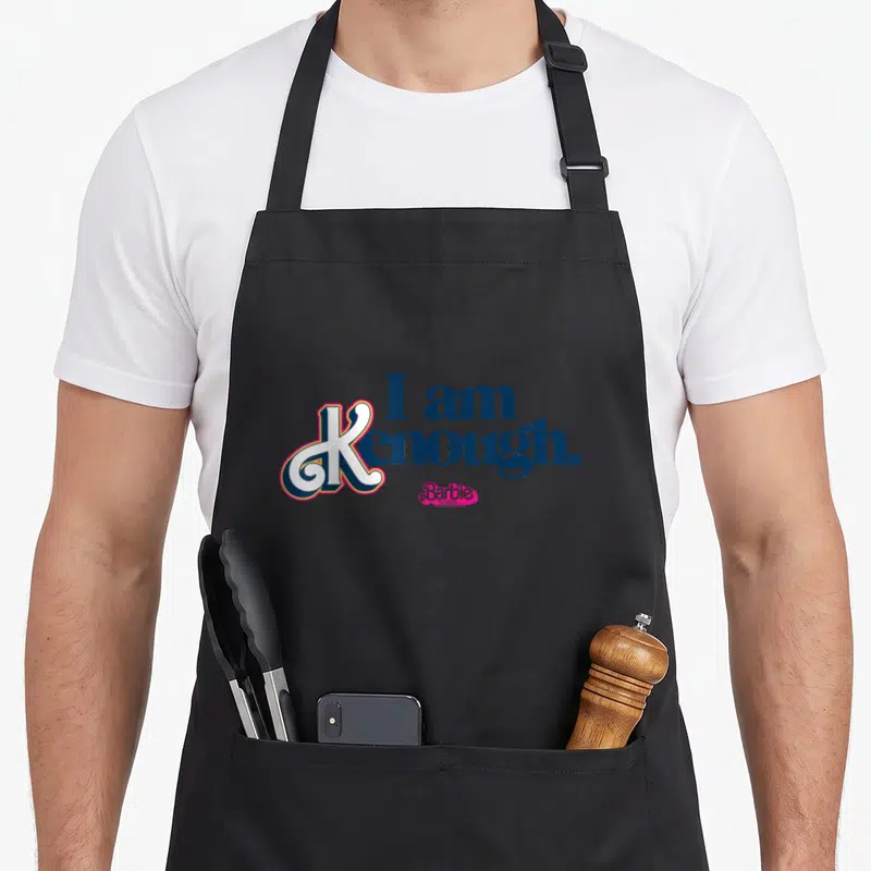 Tablier de cuisine noir avec inscription Je suis Kenough et logo Barbie en rose et bleu marine.