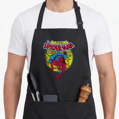 Tablier de cuisine noir avec le logo Le Merveilleux Spider-Man et le héros en position d'atterrissage sur un cercle jaune vintage.