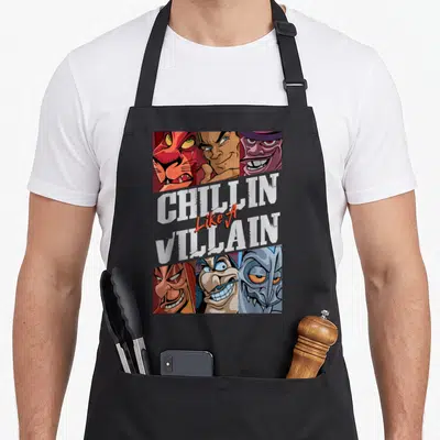 Tablier de cuisine noir avec six visages de méchants et le texte Chillin Like A Villain en lettres blanches et oranges.