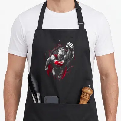 Tablier de cuisine noir avec illustration Superman Propaganda levé poing et bouclier rouge sur fond gris uni