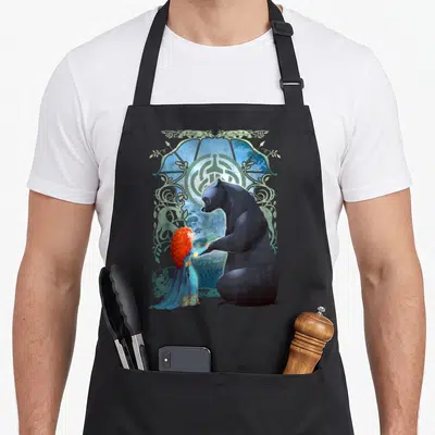 Tablier de cuisine noir avec portrait profil de Mérida et l'ours sous un motif ornemental vert et bleu.