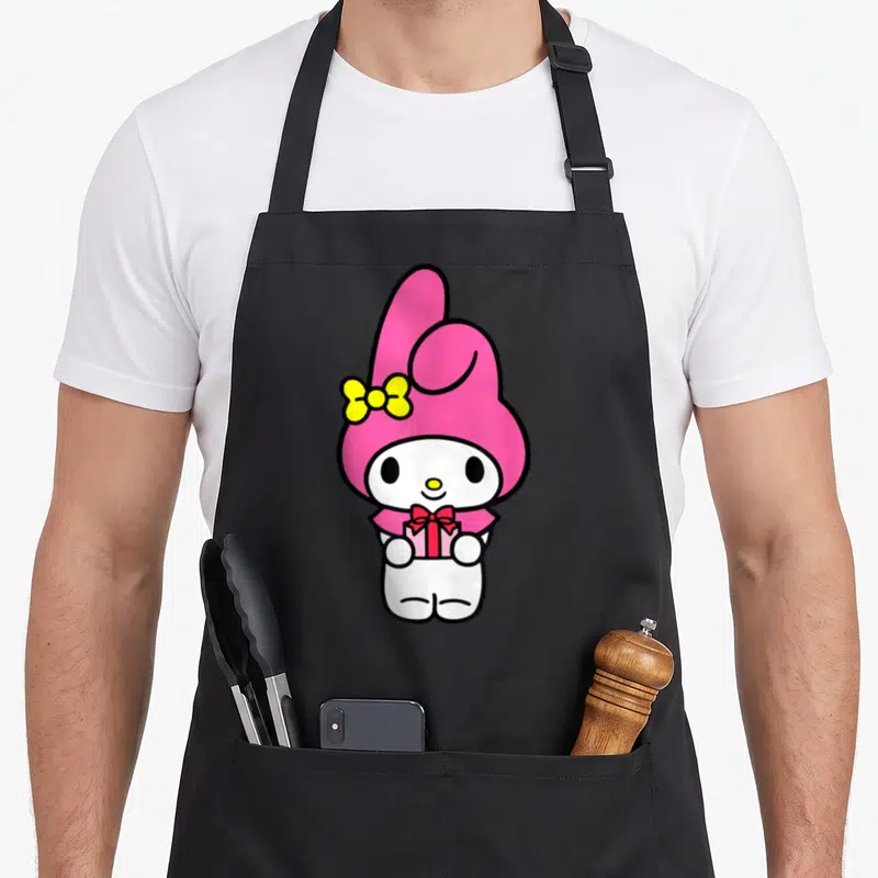 Tablier de cuisine noir avec My Melody tenant un cadeau rose et un nœud jaune sur l'oreille.