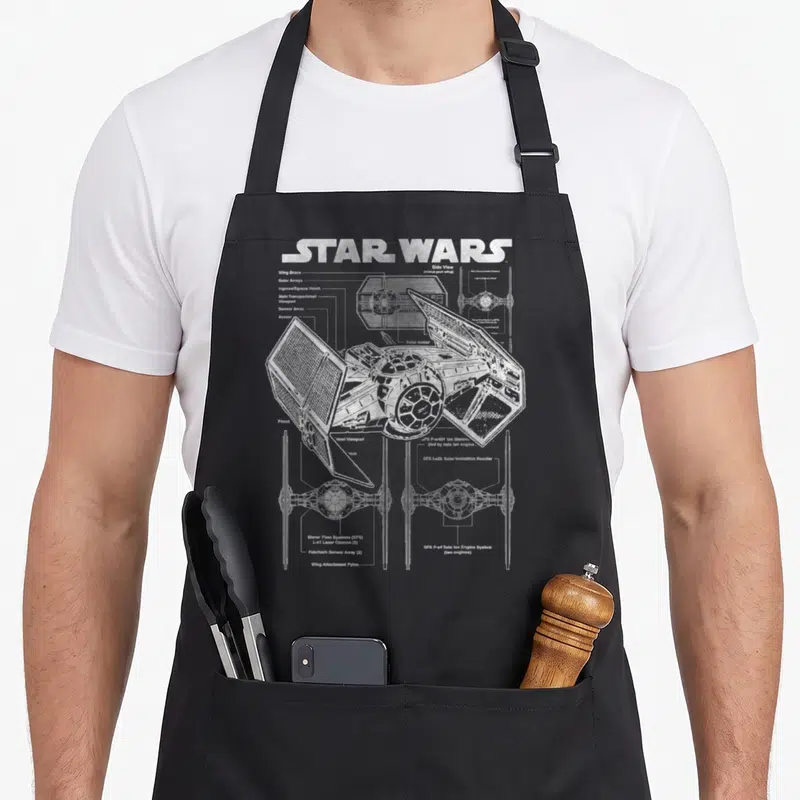 Tablier de cuisine noir avec un schéma technique blanc d'un vaisseau TIE Fighter Star Wars et ses annotations.