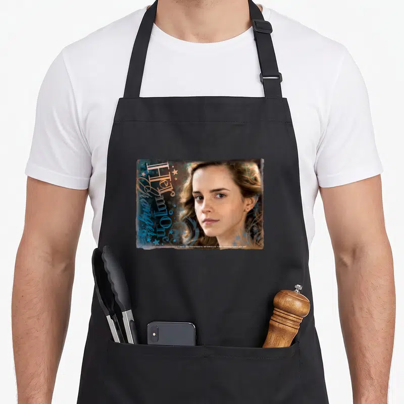 Tablier de cuisine noir avec portrait d'Hermione Granger et texte décoratif bleu étoilé.