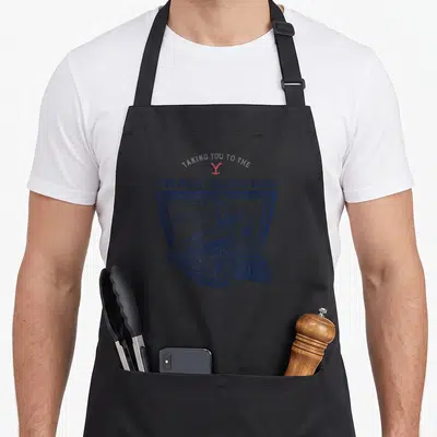 Tablier de cuisine noir avec illustration de locomotive et texte Taking you to the Train Station Yellowstone en bleu marine.