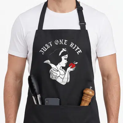 Tablier de cuisine noir avec illustration Blanche-Neige tenant une pomme rouge et texte Just One Bite en arc.