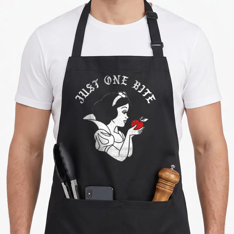 Tablier de cuisine noir avec illustration Blanche-Neige tenant une pomme rouge et texte Just One Bite en arc.