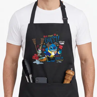 Tablier de cuisine noir avec Stitch déguisé en la Bête tenant une fleur rouge et le texte Be our GUEST.