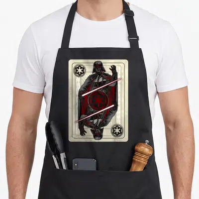 Tablier de cuisine noir avec illustration carte à jouer de Dark Vador et sabre laser rouge.