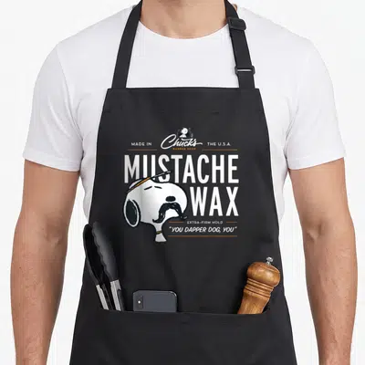 Tablier de cuisine noir avec Snoopy portant une moustache et le texte Mustache Wax en blanc.
