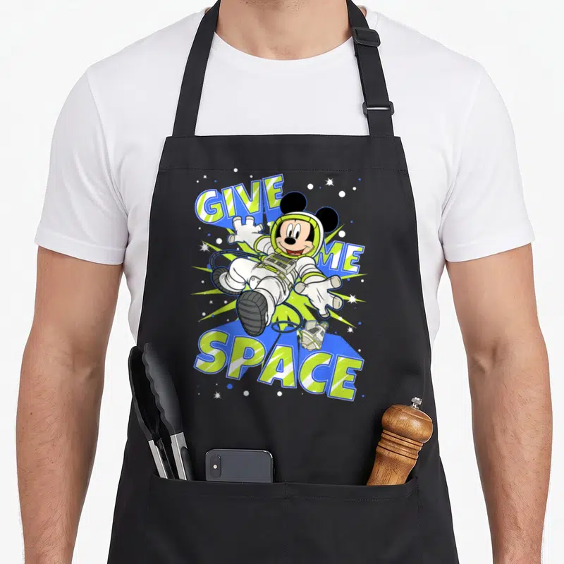 Tablier de cuisine noir avec Mickey Mouse en combinaison spatiale blanche et texte Give Me Space.