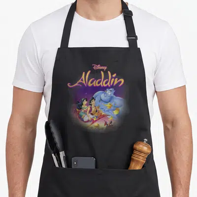 Tablier de cuisine noir avec Aladdin, Jasmine, le Genie et le logo Disney en couleurs vives.