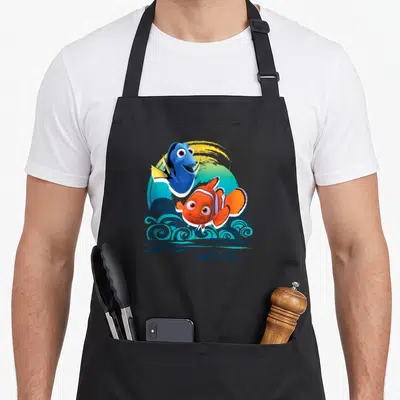 Tablier de cuisine noir avec Nemo, Dory et le texte Surf Tastic sur fond d'ondes stylisées.