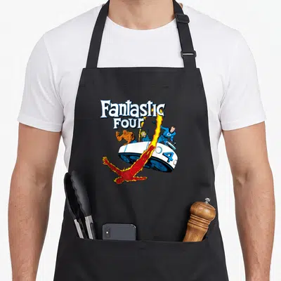 Tablier de cuisine noir avec illustration colorée des Quatre Fantastiques et leur véhicule blanc sur fond uni.