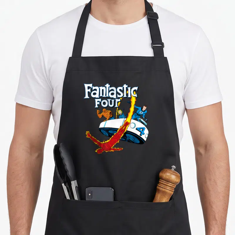Tablier de cuisine noir avec illustration colorée des Quatre Fantastiques et leur véhicule blanc sur fond uni.