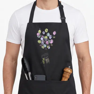 Tablier de cuisine noir avec illustration d'un couple emporté par des ballons colorés au style croquis.
